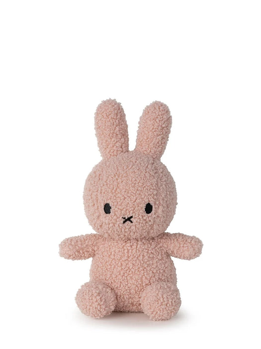 A pink, furry stuffed bunny toy is sitting on a white background.