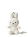 A white stuffed rabbit toy with black eyes and a black mouth is sitting on a white surface.