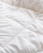 A close-up view of a white, fluffy, and wrinkled fabric, possibly a blanket or comforter.