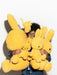 A young child is holding a large yellow stuffed rabbit in front of them, with several smaller stuffed rabbits also present.