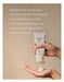 A person's hands holding a tube of CIRCA hand cream, with the cream being applied to their hand.