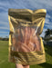 A hand holding a package of bacon strips against a blue sky background.