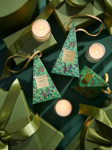 a collection of green and gold holiday-themed items, including candles, gift boxes, and ribbons, arranged on a dark background.