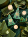 a collection of green and gold holiday-themed items, including candles, gift boxes, and ribbons, arranged on a dark background.