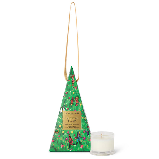 A triangular-shaped box with a Christmas tree design and a candle in a clear glass holder.