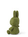 A green stuffed bunny toy is sitting on its back with its arms and legs spread out.
