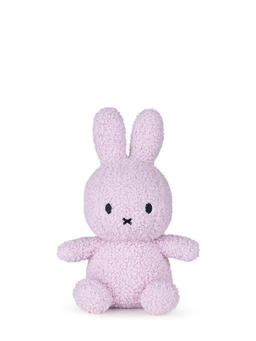 A small, pink stuffed bunny toy is sitting on a white background.