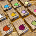 a collection of brown cardboard boxes with colorful sheep illustrations on them, arranged on a wooden surface.