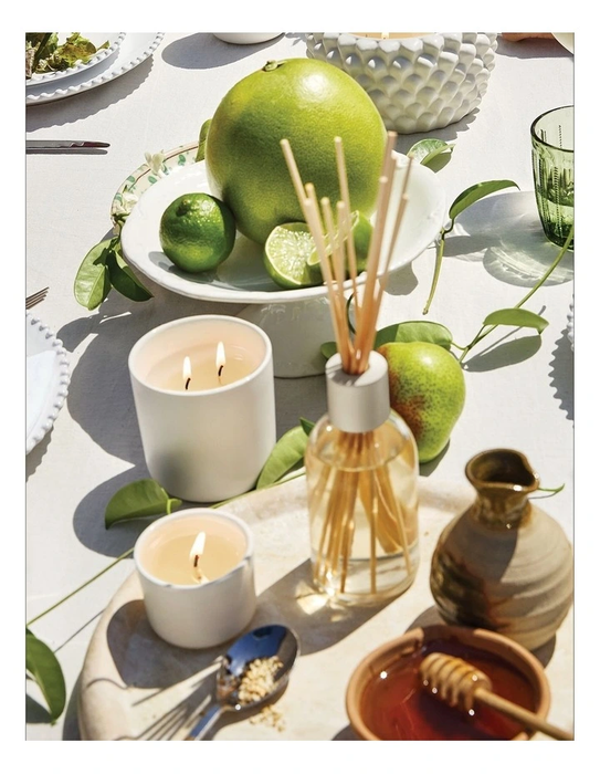 a table with various items, including a bowl of fruit, candles, a vase, and other decorative elements.