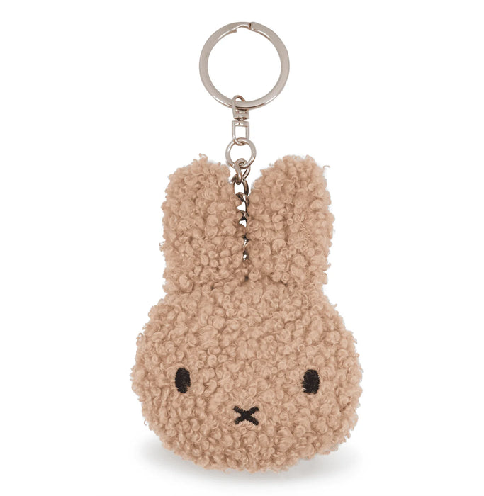 A keychain in the shape of a bunny with a fuzzy texture and a black eye and nose.