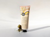 A tube of coconut and finger lime hand cream with a decorative label, placed on a white surface with a few pieces of the cream visible.