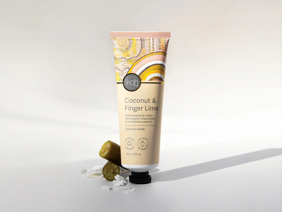 A tube of coconut and finger lime hand cream with a decorative label, placed on a white surface with a few pieces of the cream visible.