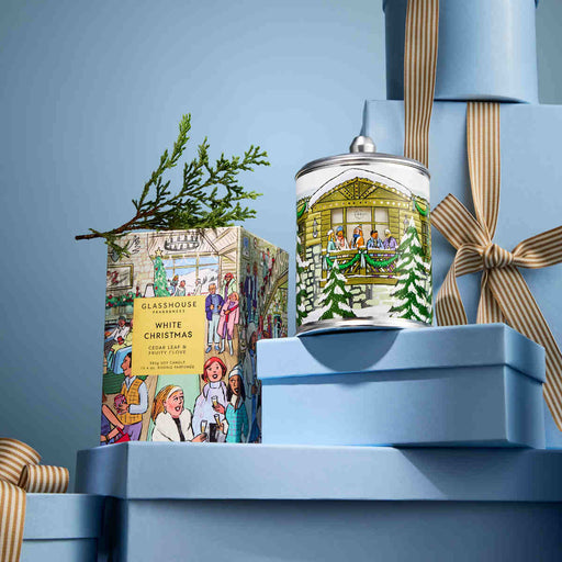 a collection of Christmas-themed items, including a box of white Christmas tea, a tin candle, and a stack of gift boxes.