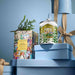 a collection of Christmas-themed items, including a box of white Christmas tea, a tin candle, and a stack of gift boxes.