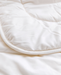 A close-up view of a white, fluffy, and wrinkled fabric, possibly a blanket or quilt.