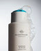 A bottle of Glasshouse Fragrances shampoo with a blue cap, surrounded by bubbles, with the label reading "Midnight in Milan Saffron & Rose".